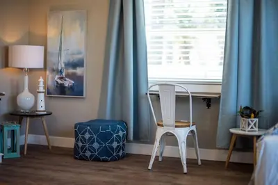 a white chair sitting in front of a window with blue curtains at #753Coastal Anchor Suite!GroundLevel/Parking/Grill in San Diego