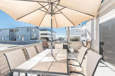 a table and chairs with an umbrella on a balcony at 3Br Oceanview Corner Retreat One House From The Beach By Beachview Rentals in Newport Beach