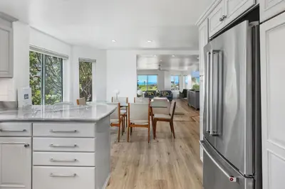 a kitchen with white cabinets and a dining room at Surf Song Symphony - SONG55 in Solana Beach