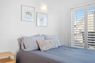 a bedroom with a bed with blue sheets and a window at Mission Beach 3BR Gem Rooftop Patio and Hot Tub in San Diego