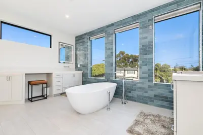 a bathroom with a tub and a sink and windows at Luxury Pool Haven Scenic Views and Summer Fireworks in San Diego