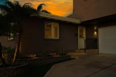 a house with a palm tree in front of a sunset at Chic Retreat Ping Pong, Bonfires and Patio Leisure in San Diego