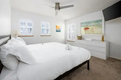 a white bedroom with a large white bed and windows at Steps From the Beach & Belmont in San Diego