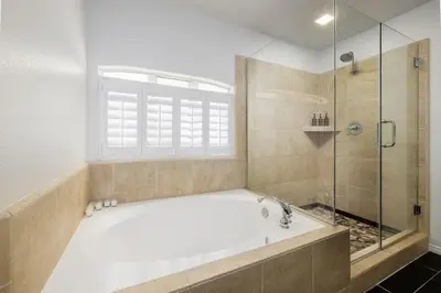 a bathroom with a tub and a glass shower at Steps From the Beach & Belmont in San Diego