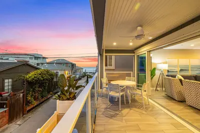 a balcony of a house with a table and chairs at Ocean Breeze and Rooftop Views Steps to Surf and Sun in San Diego