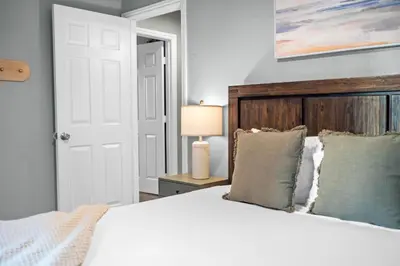 a bedroom with a white bed with a wooden headboard at Modern Oceanside Stay with Yard & Laidback Vibes in Oceanside