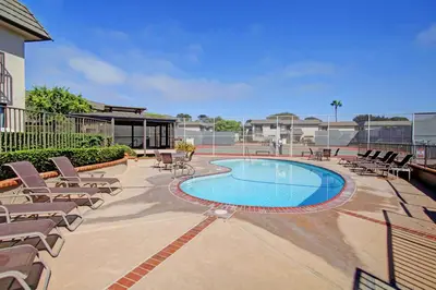 a swimming pool with chaises and lounge chairs next to a building at Solana Beach Escape, Beach Access, AC, Pools, Spa, Tennis Courts & Clubhouse Views in Solana Beach