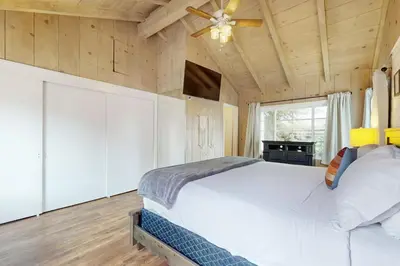 a bedroom with a white bed and a ceiling fan at La Jolla Historic Gem, Hot Tub, Game Room, Garden Oasis with Firepit & Courtyard Dining in San Diego