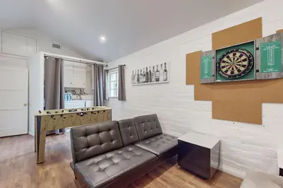 a living room with a couch and a dart board on the wall at La Jolla Historic Gem, Hot Tub, Game Room, Garden Oasis with Firepit & Courtyard Dining in San Diego