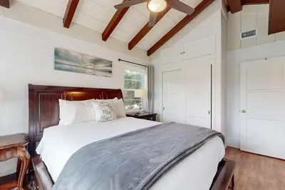 a bedroom with a large bed with a wooden headboard at La Jolla Historic Gem, Hot Tub, Game Room, Garden Oasis with Firepit & Courtyard Dining in San Diego