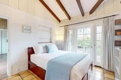 a white bedroom with a bed and a window at La Jolla Historic Gem, Hot Tub, Game Room, Garden Oasis with Firepit & Courtyard Dining in San Diego