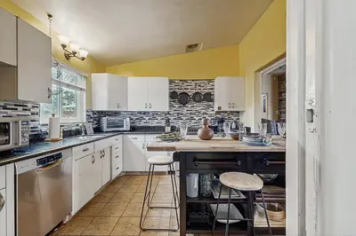 a kitchen with white cabinets and a counter with stools at Seabreeze Bungalow in Oceanside