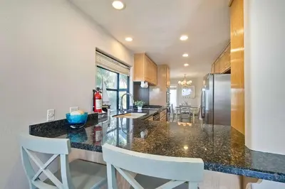 a kitchen with a counter and two white chairs in it at Beachfront Sunset in Encinitas