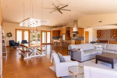 a living room with white furniture and a kitchen at Luxury Mountain Estate Sleeps 11 in Valley Center
