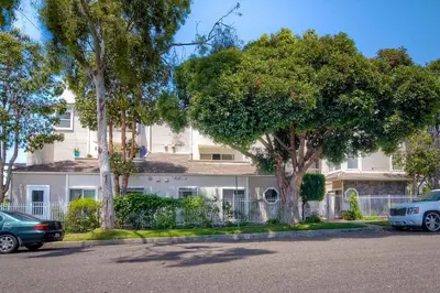 a building with trees and cars parked in front of it at Silver Surf Getaway in Oceanside