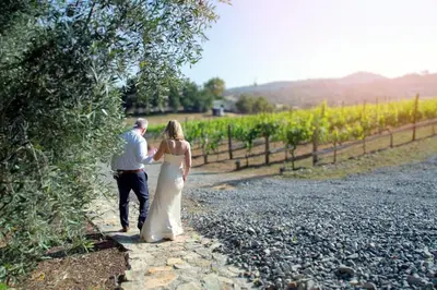 a bride and groom walking down a gravel road at Casita Vino Dog-Friendly Vineyard Retreat & Stay in Escondido