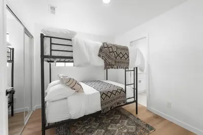 two bunk beds in a white room with a rug at Walk to Mission Bay Firepit AC Putting Green in San Diego