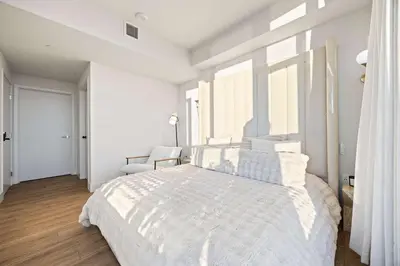 a white bedroom with a large bed and a chair at Penthouse High-Rise Ocean & City Views in San Diego