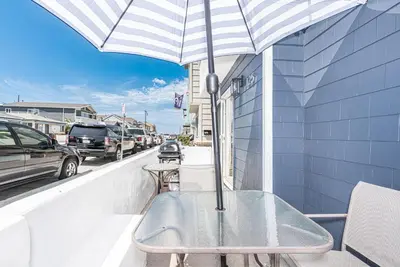 a table with an umbrella on a balcony at Renovated 3Br W Stylish Interior Steps From 29Th St Beach By Beachview Rentals in Newport Beach
