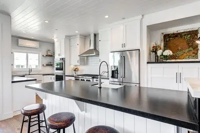 a kitchen with white cabinets and a black counter top at 3Br Luxury Condo W Rooftop Deck, Fire Pit, Steps To Sand By Beachview Rentals in Newport Beach
