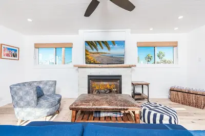 a living room with a blue couch and a fireplace at 3Br Luxury Condo W Rooftop Deck, Fire Pit, Steps To Sand By Beachview Rentals in Newport Beach