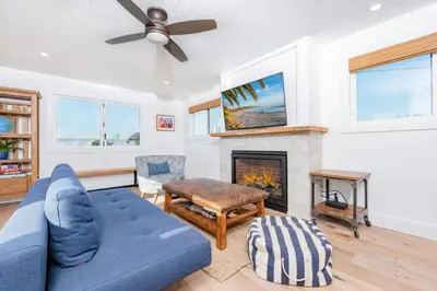 a living room with a blue couch and a fireplace at 3Br Luxury Condo W Rooftop Deck, Fire Pit, Steps To Sand By Beachview Rentals in Newport Beach