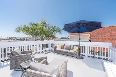 a patio with chairs and an umbrella at Pet-Friendly 3Br W Ac, Rooftop Deck, 2 Houses From Beach By Beachview Rentals in Newport Beach