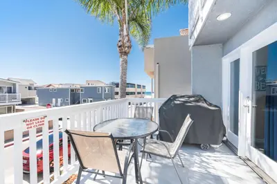 a table and chairs on a balcony with a palm tree at Pet-Friendly 3Br W Ac, Rooftop Deck, 2 Houses From Beach By Beachview Rentals in Newport Beach