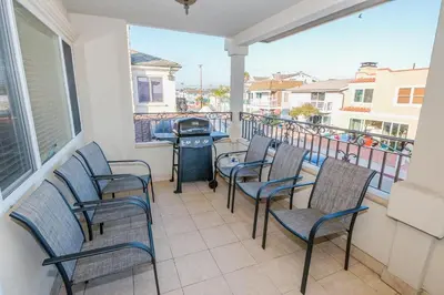 a patio with chairs and a grill on a balcony at Spacious 4Br W Oceanview Balcony, 3 Houses From The Beach By Beachview Rentals in Newport Beach