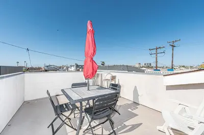 a patio table with chairs and an umbrella on a roof at Family-Friendly 3Br Steps From Beach - Walk To Everything By Beachview Rentals in Newport Beach