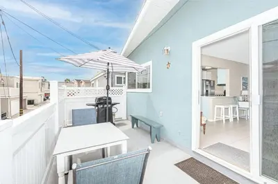 a patio with a table and an umbrella on a balcony at Upgraded 5Br Summer Vacation Home, Steps From The Sand By Beachview Rentals in Newport Beach