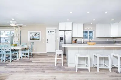 a kitchen with white cabinets and a table and chairs at Cozy Family Beach Home Half Block To Popular 44Th St Beach By Beachview Rentals in Newport Beach