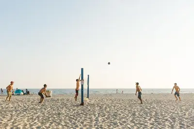 a group of men playing a game of volley ball on the beach at Modern Oceanview Tri-Level Condo Steps From The Beach By Beachview Rentals in Newport Beach
