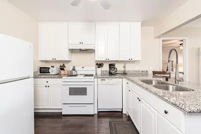 a white kitchen with white cabinets and a sink at Spacious 4Br Retreat W Rooftop Deck One Block From Beach By Beachview Rentals in Newport Beach