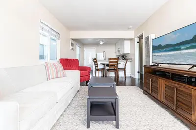 a living room with a white couch and a flat screen tv at Spacious 4Br Retreat W Rooftop Deck One Block From Beach By Beachview Rentals in Newport Beach