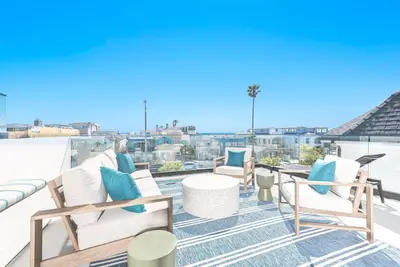a patio with chairs and tables on a roof at Luxury 3Br W Rooftop Deck, Grill, Ac, Steps From The Sand By Beachview Rentals in Newport Beach