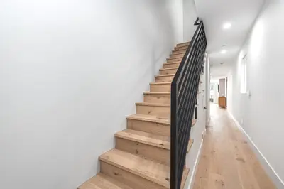 a staircase in a house with white walls and wooden floors at Luxury 3Br W Rooftop Deck, Grill, Ac, Steps From The Sand By Beachview Rentals in Newport Beach