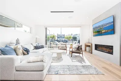 a living room with a couch and a fireplace at Luxury 3Br W Rooftop Deck, Grill, Ac, Steps From The Sand By Beachview Rentals in Newport Beach