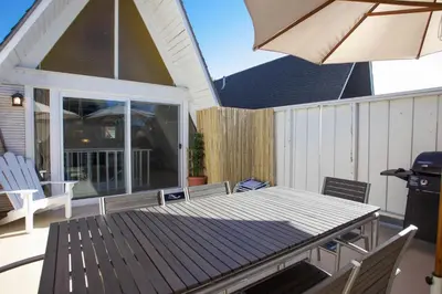 a patio with a table and chairs and an umbrella at Retro A-Frame Studio W Loft And Sun Deck, Steps From Sand By Beachview Rentals in Newport Beach