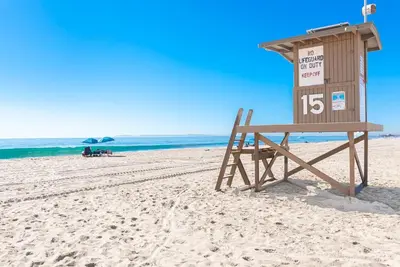a lifeguard stand on a beach with a sign at Retro A-Frame Studio W Loft And Sun Deck, Steps From Sand By Beachview Rentals in Newport Beach