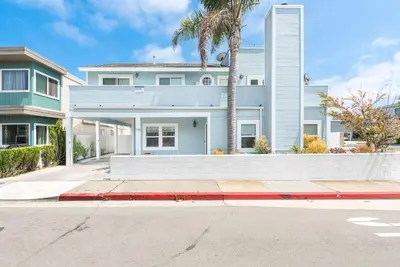 a blue house with a palm tree in front of a street at Charming 3Br Beach Home W Rooftop Deck One Block From Sand By Beachview Rentals in Newport Beach