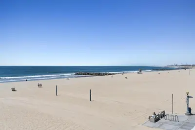 a beach with people on the sand and the ocean at Modern 3Br Oceanfront W Rooftop Deck And Panoramic Views By Beachview Rentals in Newport Beach