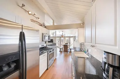 a large kitchen with white cabinets and a stainless steel refrigerator at Spacious 6Br W Oceanview And Garden Patio, Steps To Sand By Beachview Rentals in Newport Beach
