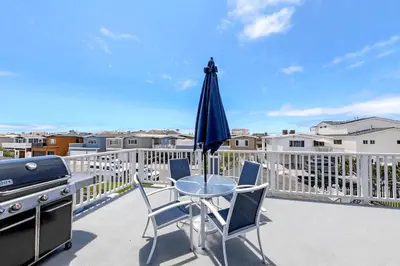 a patio with a table and a grill and an umbrella at Spacious 6Br W Oceanview And Garden Patio, Steps To Sand By Beachview Rentals in Newport Beach