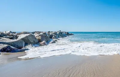 a beach with rocks and the ocean on a sunny day at Spacious 6Br W Oceanview And Garden Patio, Steps To Sand By Beachview Rentals in Newport Beach
