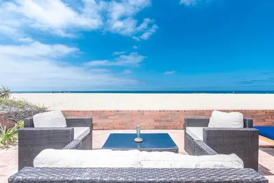 a patio with wicker chairs and a table and the beach at Remodeled 2Br Oceanfront W Spacious Patio, Stunning Views By Beachview Rentals in Newport Beach