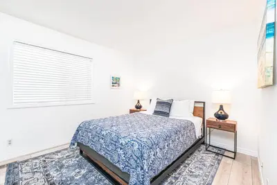a white bedroom with a bed and two lamps at Remodeled 2Br Oceanfront W Spacious Patio, Stunning Views By Beachview Rentals in Newport Beach