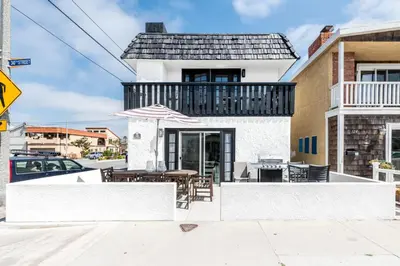 a house with a balcony with a table and chairs at Stylish 6Br Duplex, One Block From Beach And Boardwalk By Beachview Rentals in Newport Beach