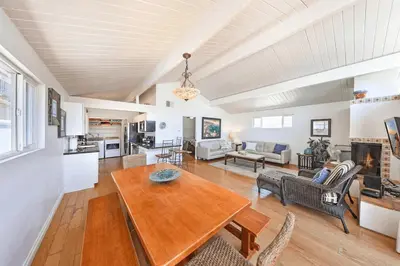 a living room with a wooden table and a couch at Charming 4Br W Large Garden Patio, 2 Houses From The Sand By Beachview Rentals in Newport Beach