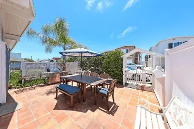 a patio with a table and chairs and an umbrella at Charming 4Br W Large Garden Patio, 2 Houses From The Sand By Beachview Rentals in Newport Beach
